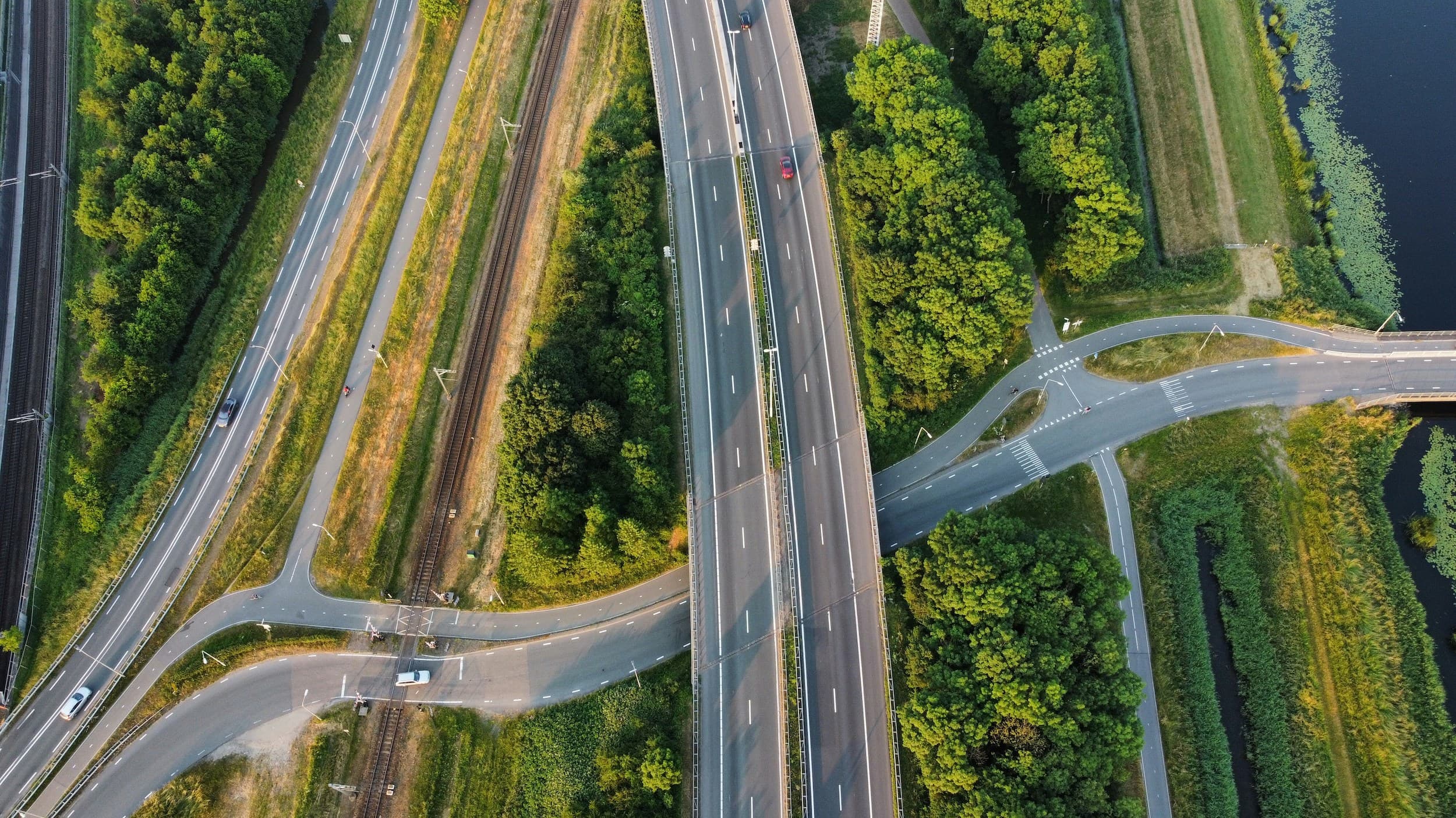 Luchtfoto van Nederlandse infrastructuur: snelweg, spoor en groen landschap